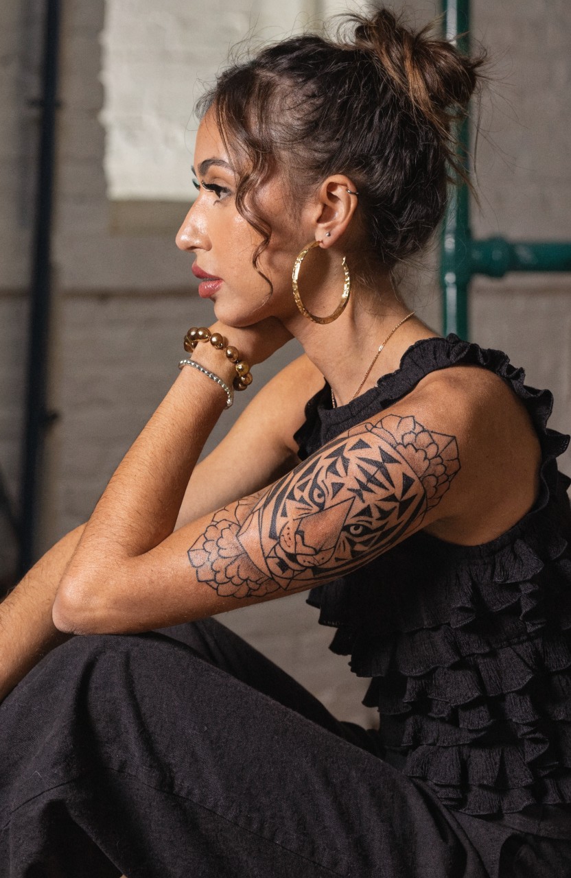Black linework tiger face tattoo integrated with mandala floral patterns on a woman's upper arm