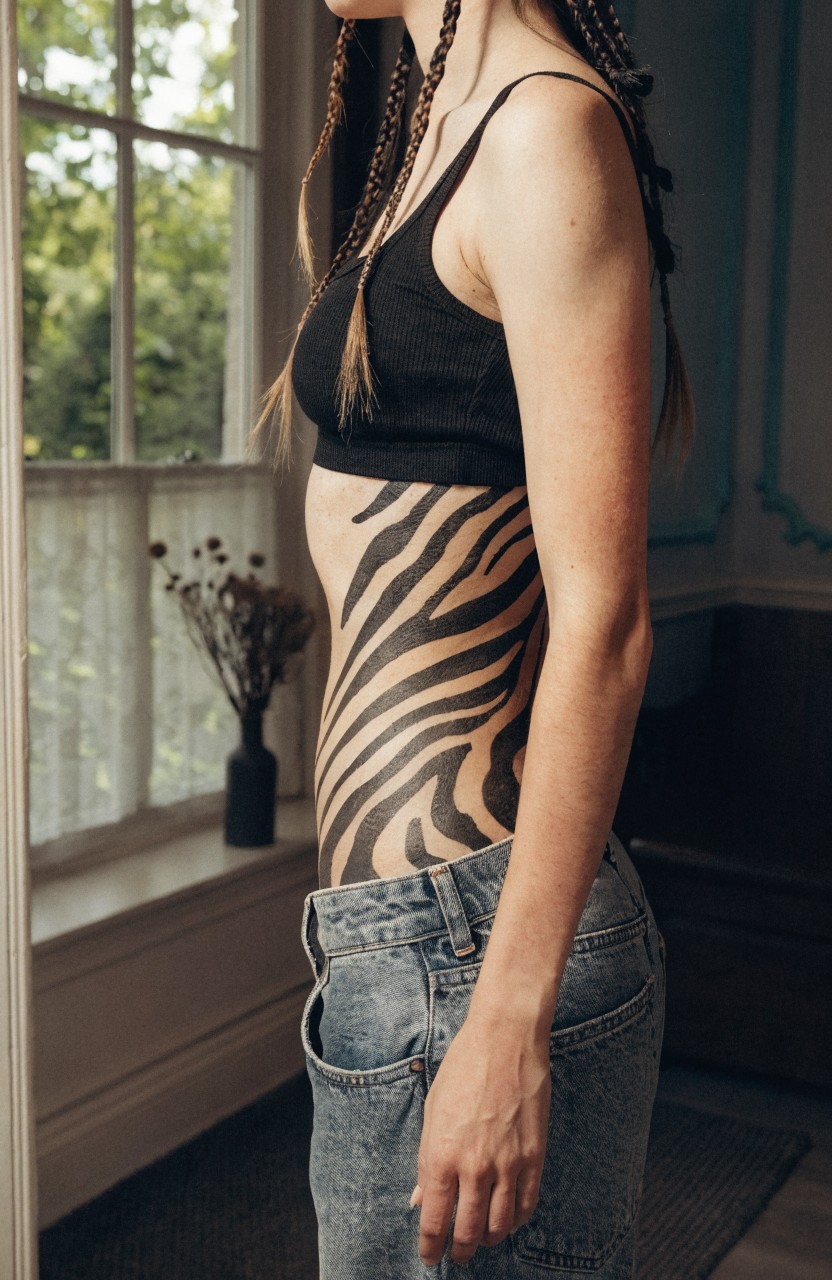 Black tiger stripe tattoo curving down a woman's side torso from underbust to hip
