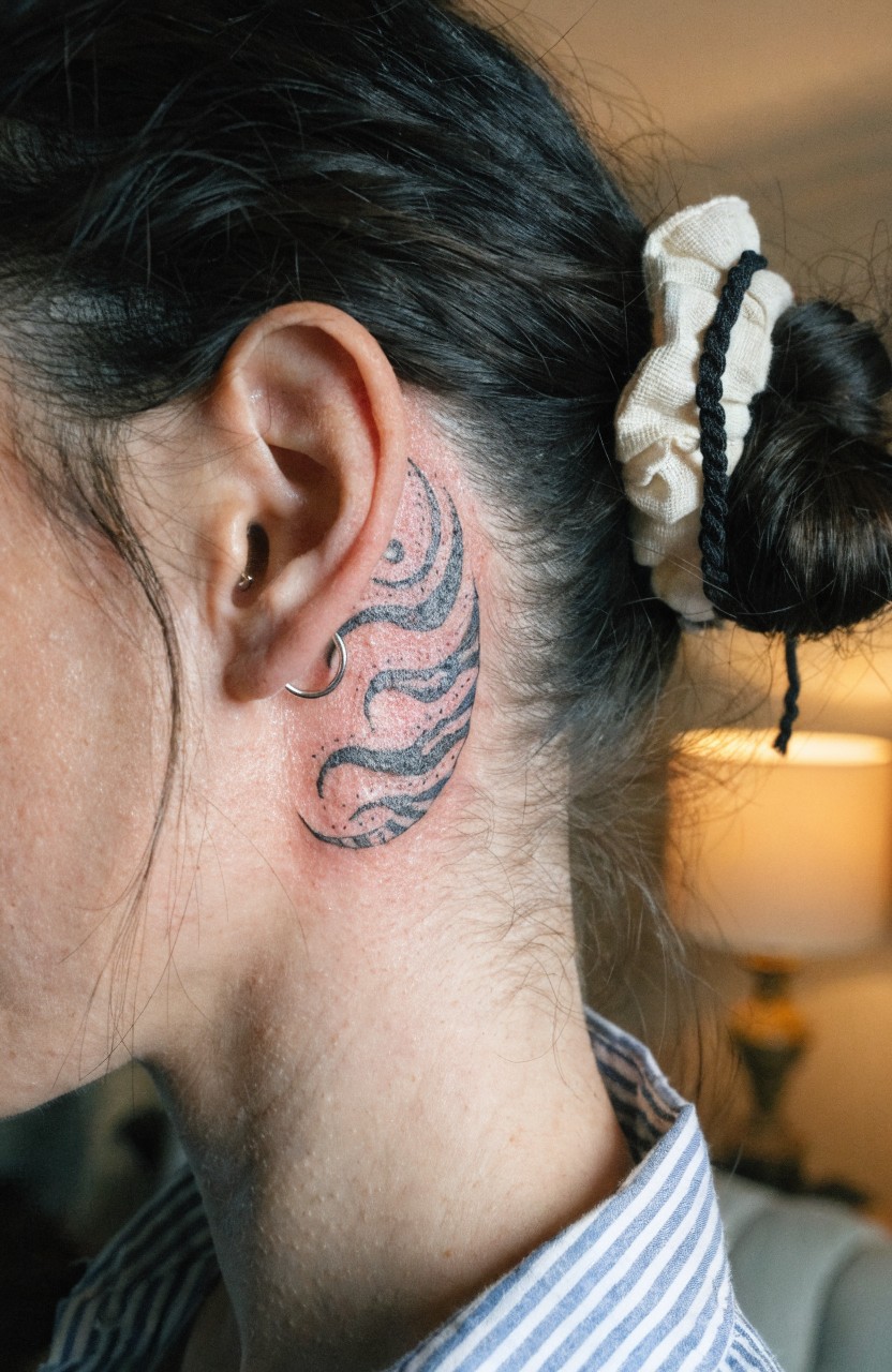 Black ink swirling tiger stripes tattooed behind a woman's ear on her neck base, hair in white scrunchie