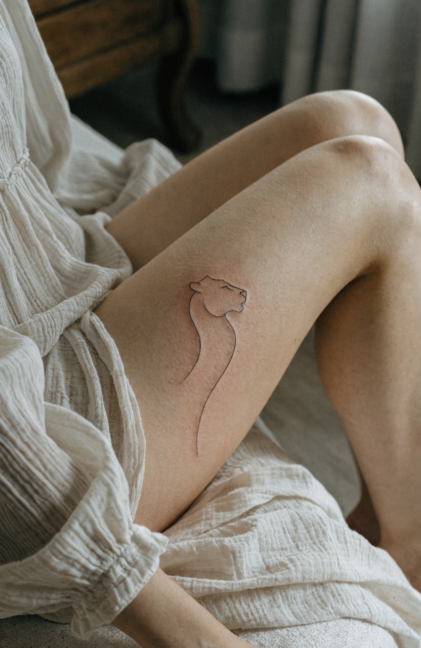Minimalist line art lion silhouette tattoo on outer thigh under white dress