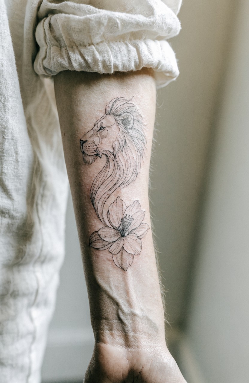 Black linework tattoo of lion head profile morphing into blooming flower on outer forearm