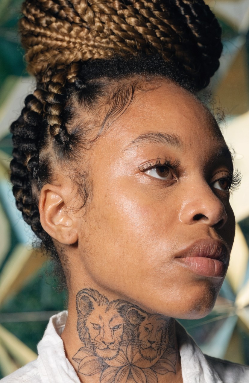 Symmetrical black ink neck tattoo with two realistic lion heads facing each other and connected by central floral elements