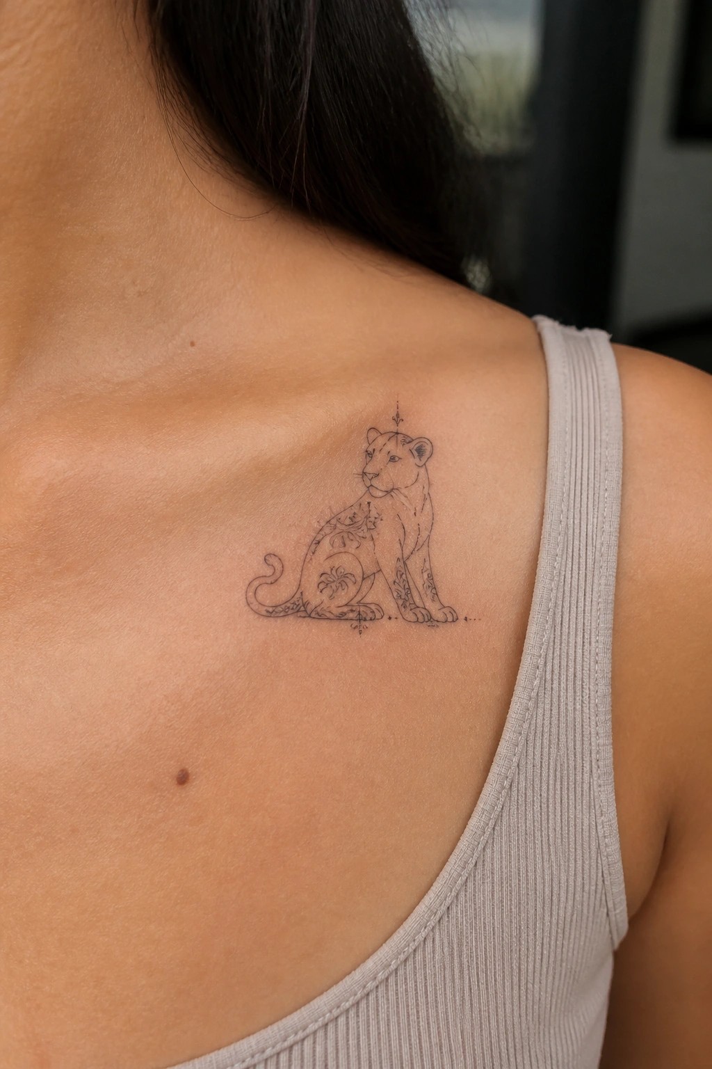 Floral lioness tattoo on shoulder above light tank top strap
