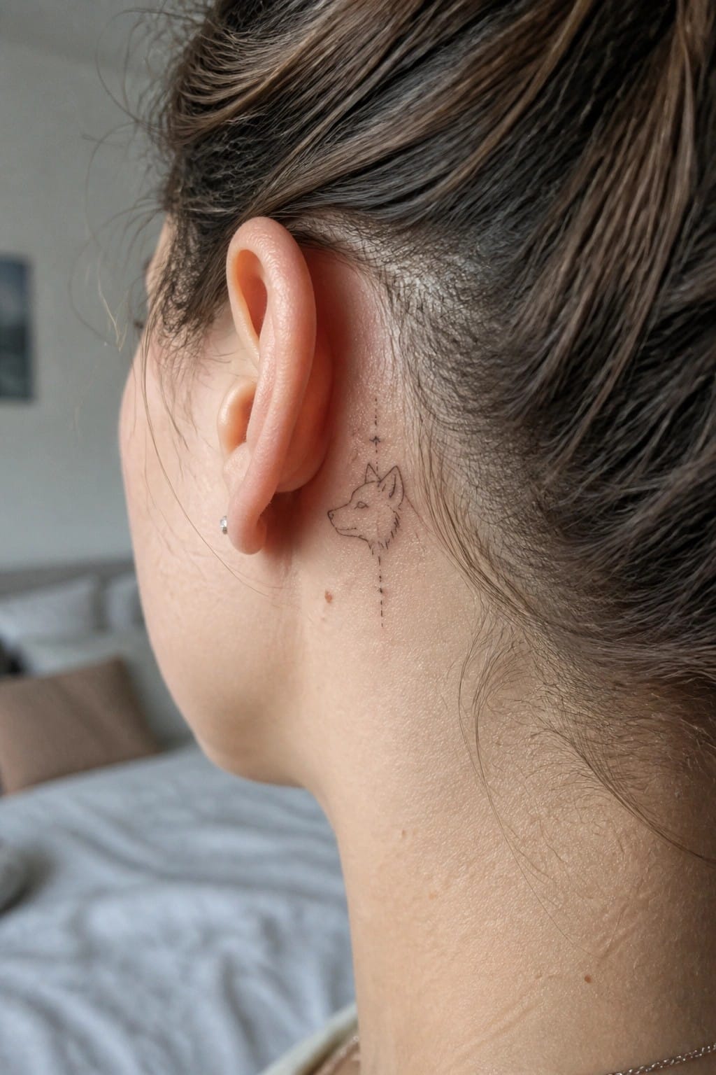 Woman's ear with wolf-head tattoo and dotted line on neck skin