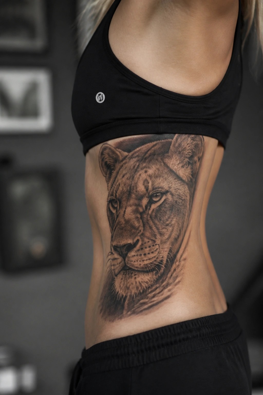 Woman with large lioness tattoo on side, wearing black sports bra.