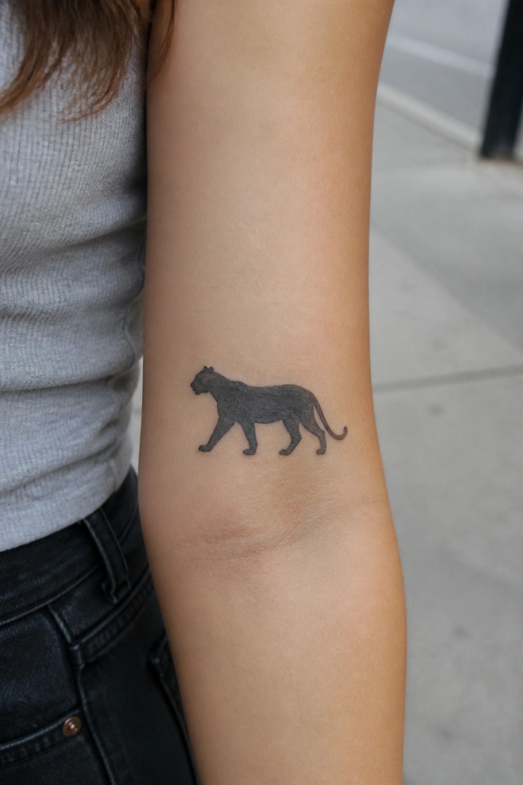 Black panther tattoo on forearm with gray shirt and black pants