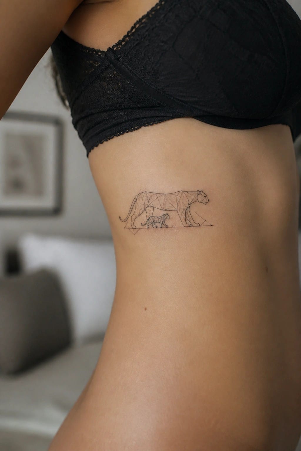 Woman's side torso in black lace bra with geometric lion tattoo on ribs