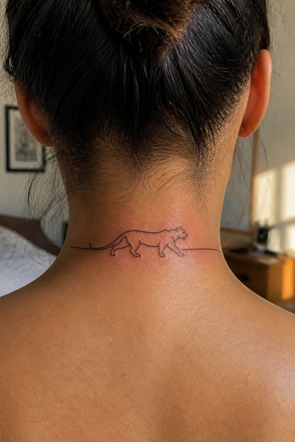 Minimalist black line tattoo of a walking lioness integrated into a straight horizontal line across the back of the neck