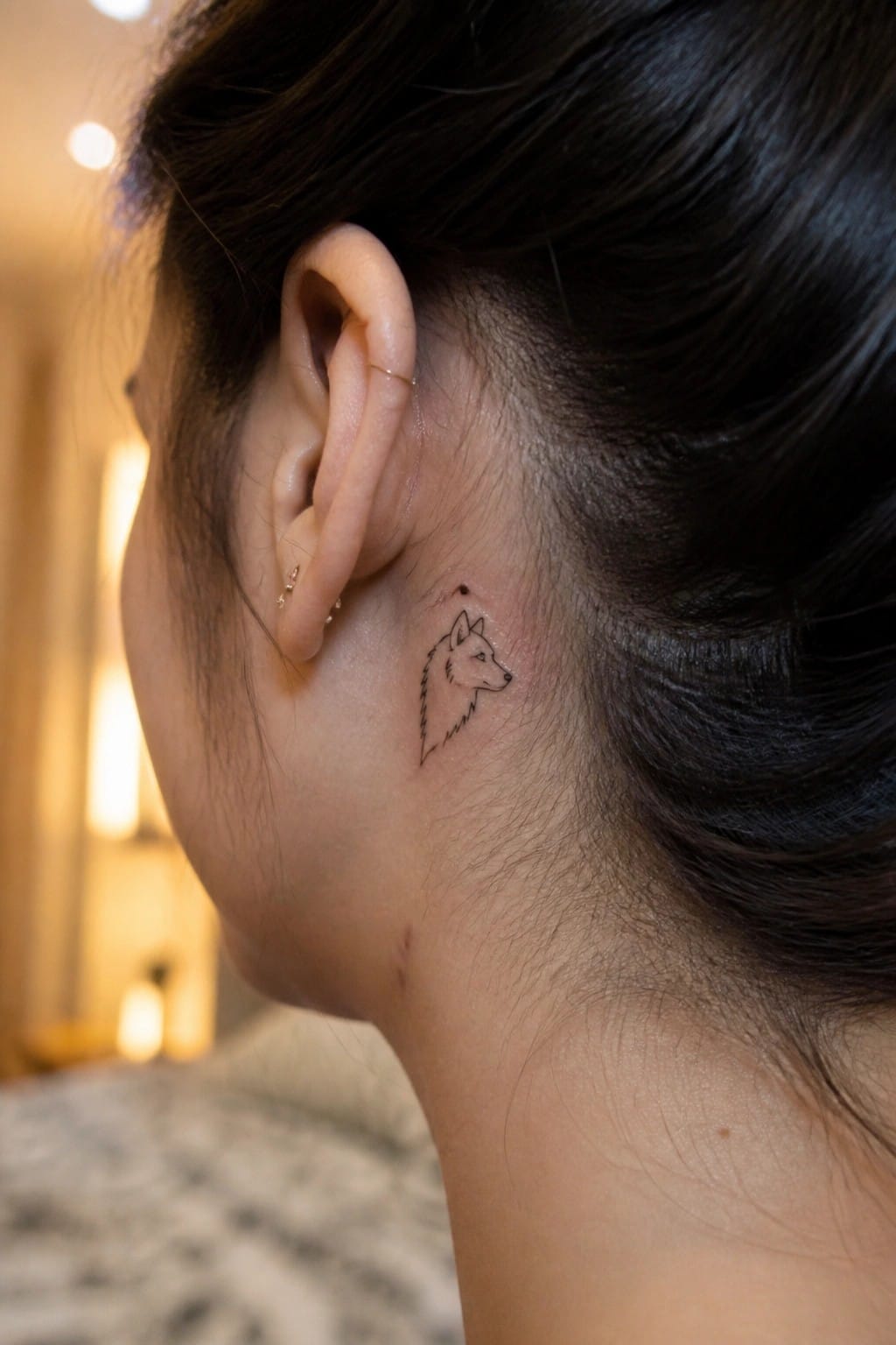 Profile view of ear with wolf head tattoo and gold hoop earrings