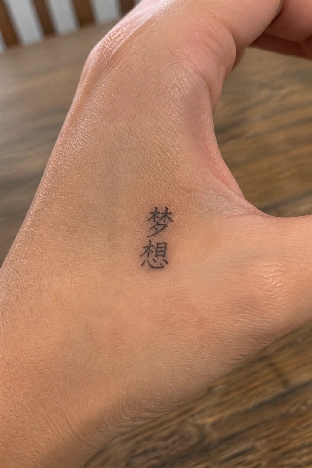 Close-up of light-skinned palm with two black Chinese character tattoos.