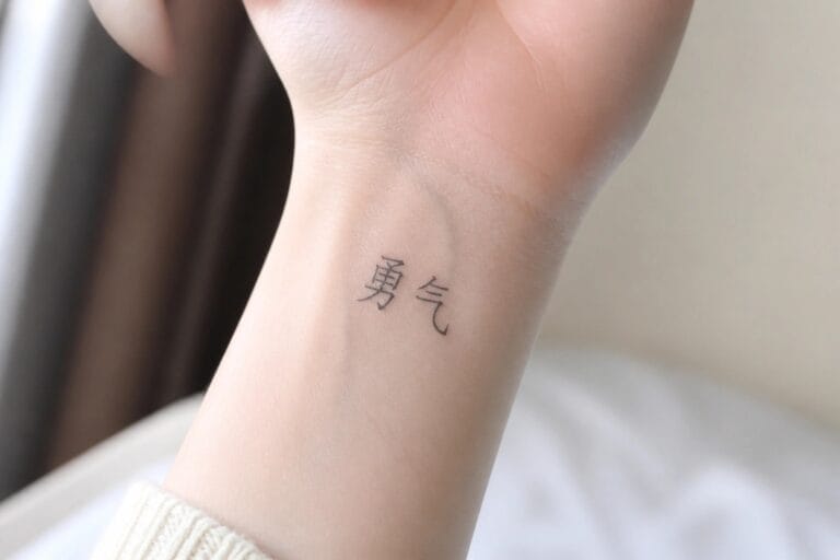 Clenched fist showing black Chinese characters tattooed on inner wrist above beige sleeve