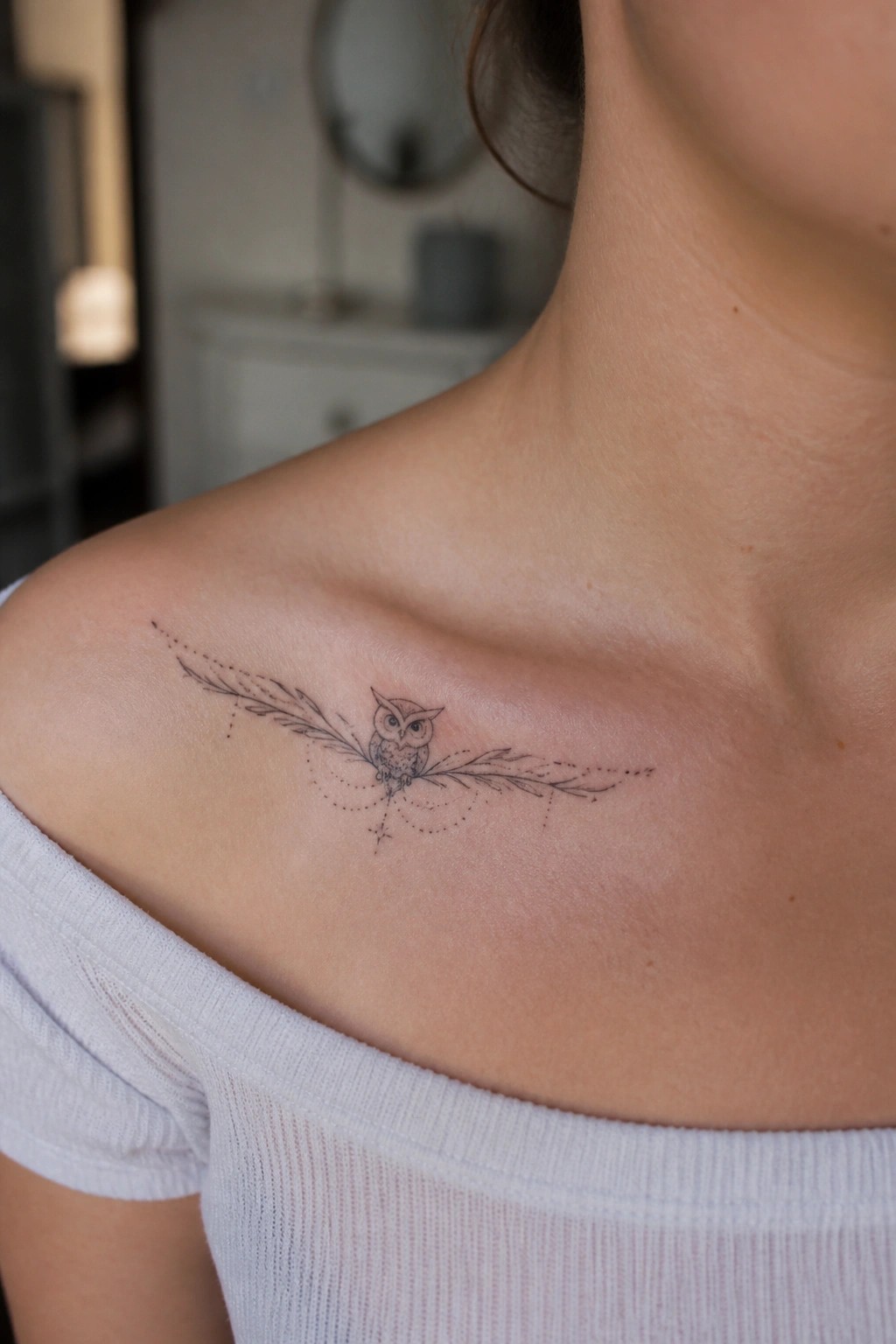 Owl tattoo with feathered wings and dotted lines on shoulder, white off-shoulder top.