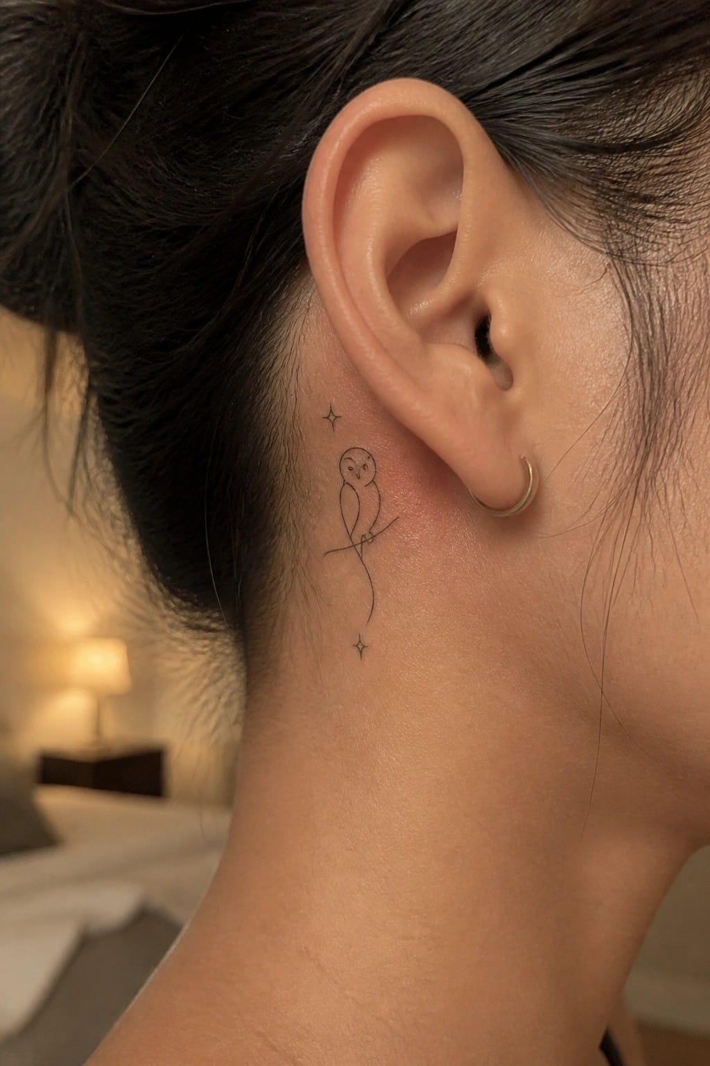 Minimalist owl line tattoo behind ear with stars and gold hoop earring
