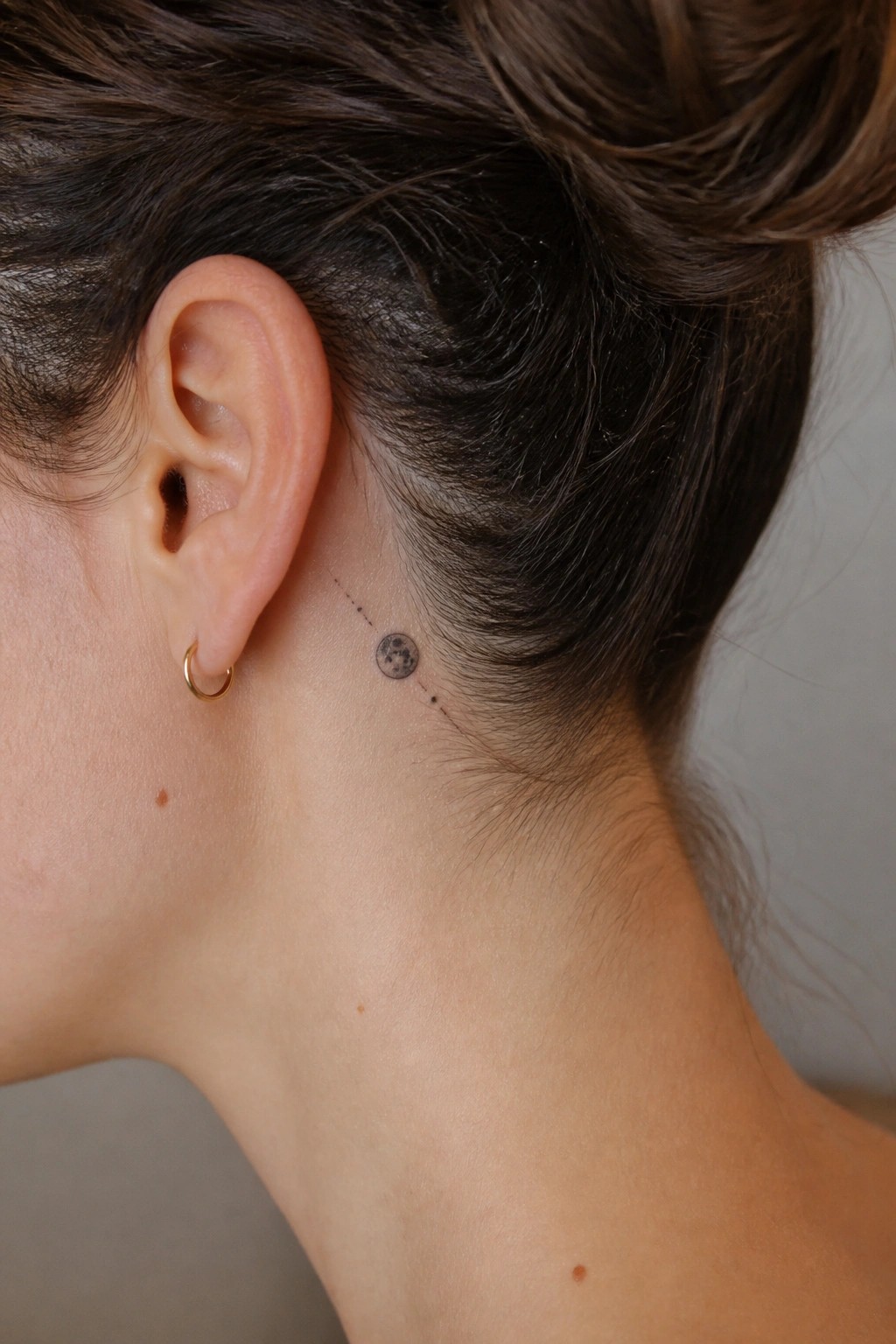 Small moon tattoo with dotted lines placed behind the ear on the side of the neck