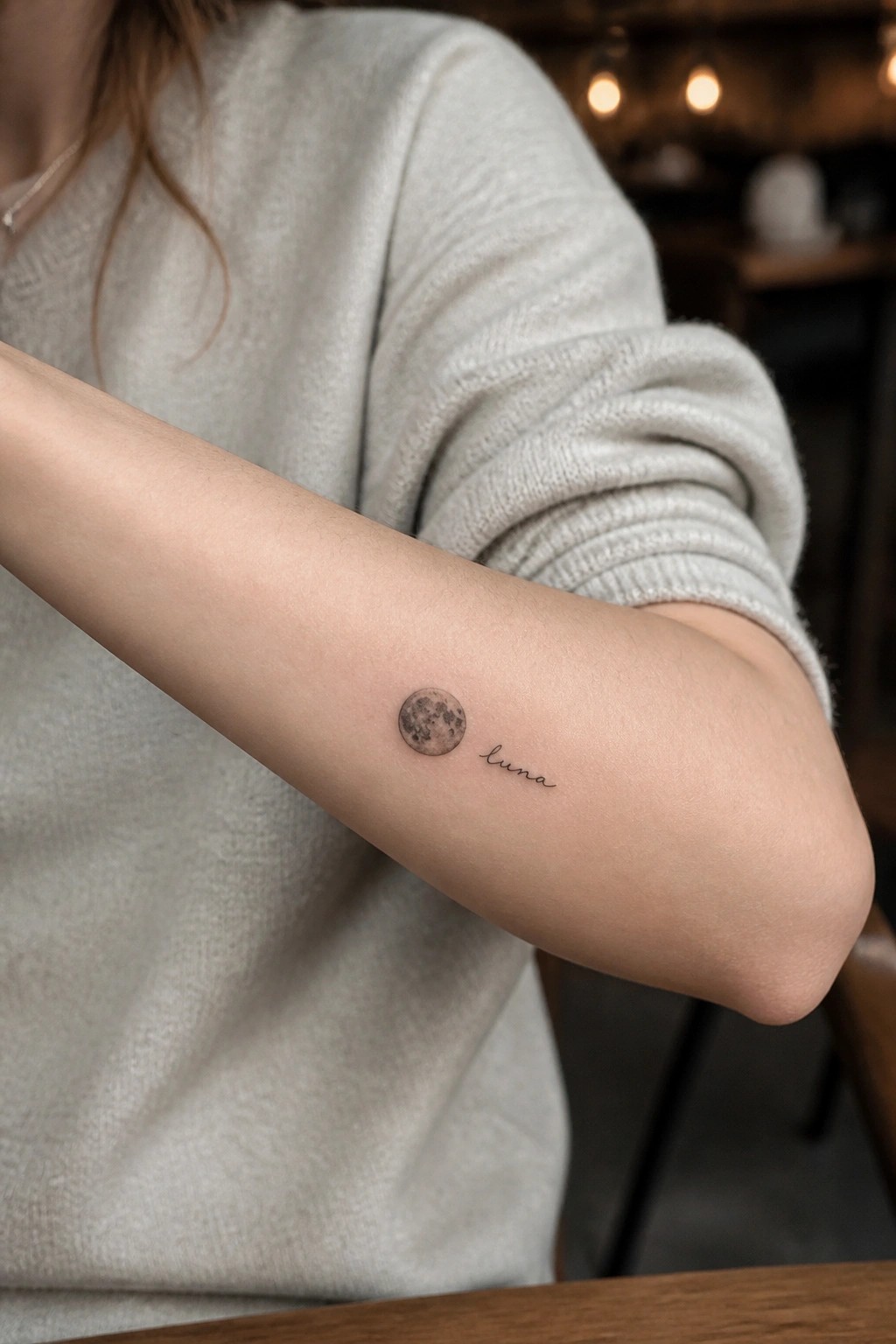 Small realistic full moon tattoo with luna script on the inner forearm