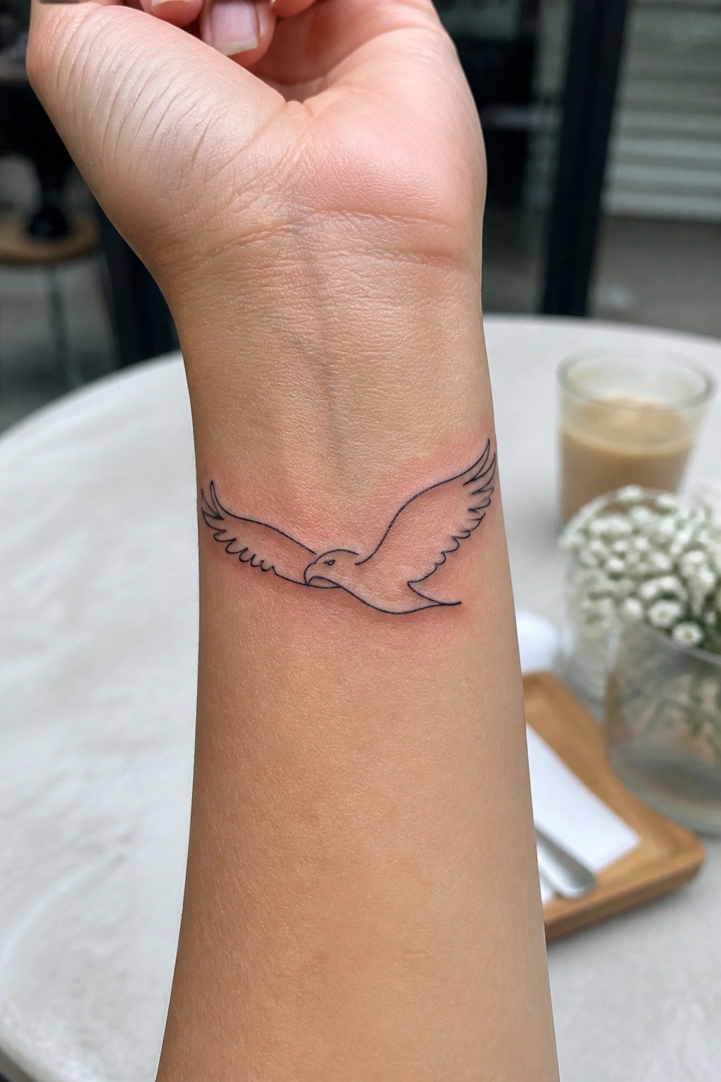 Line-art eagle tattoo on a wrist with fresh surrounding redness