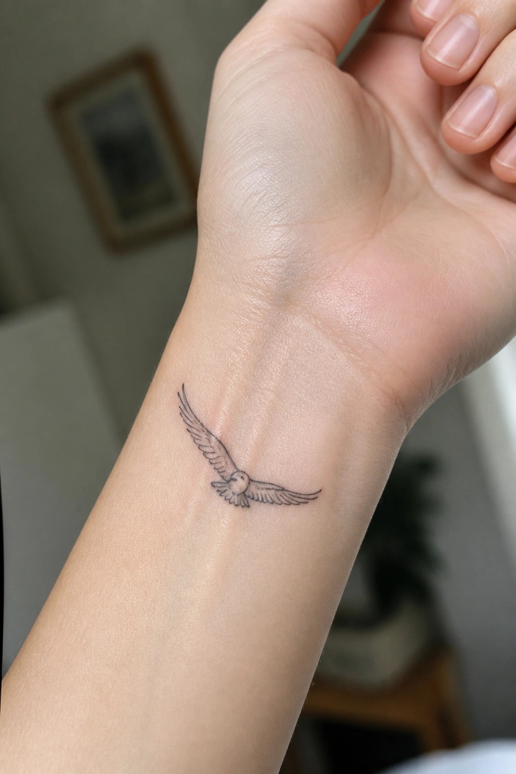 Small fine line eagle tattoo with spread wings on the inner wrist