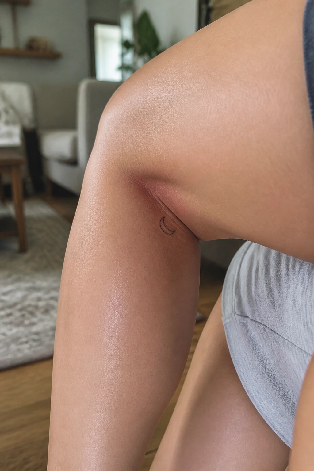 Close-up of elbow with small crescent moon tattoo beside reddish mark on skin