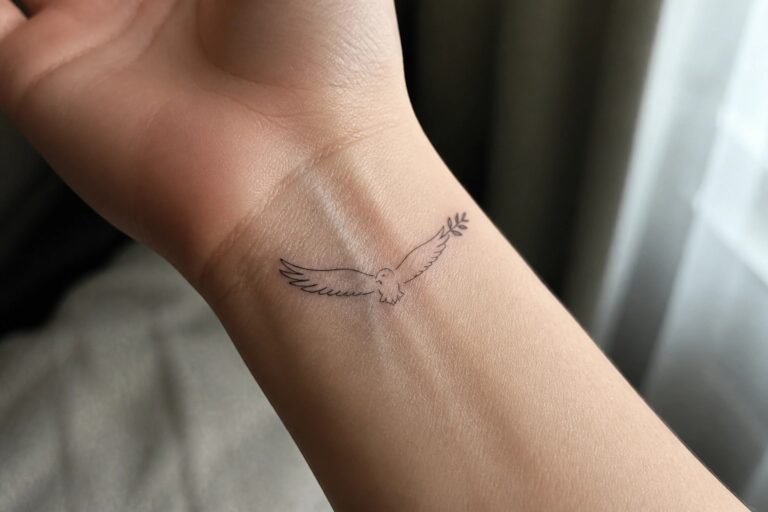 19 Spiritual Eagle Tattoo Ideas for Women Inspired by Personal Growth Small fine line tattoo of a flying bird holding a branch on the inner wrist.
