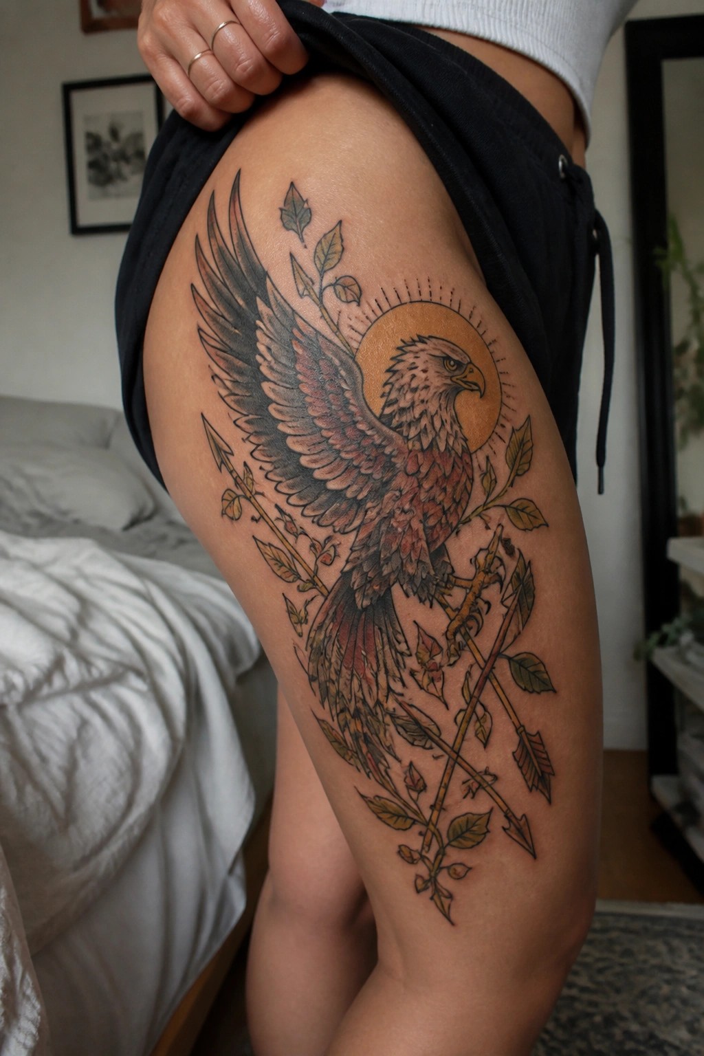 Large eagle tattoo with spread wings, arrows, and leaves on thigh
