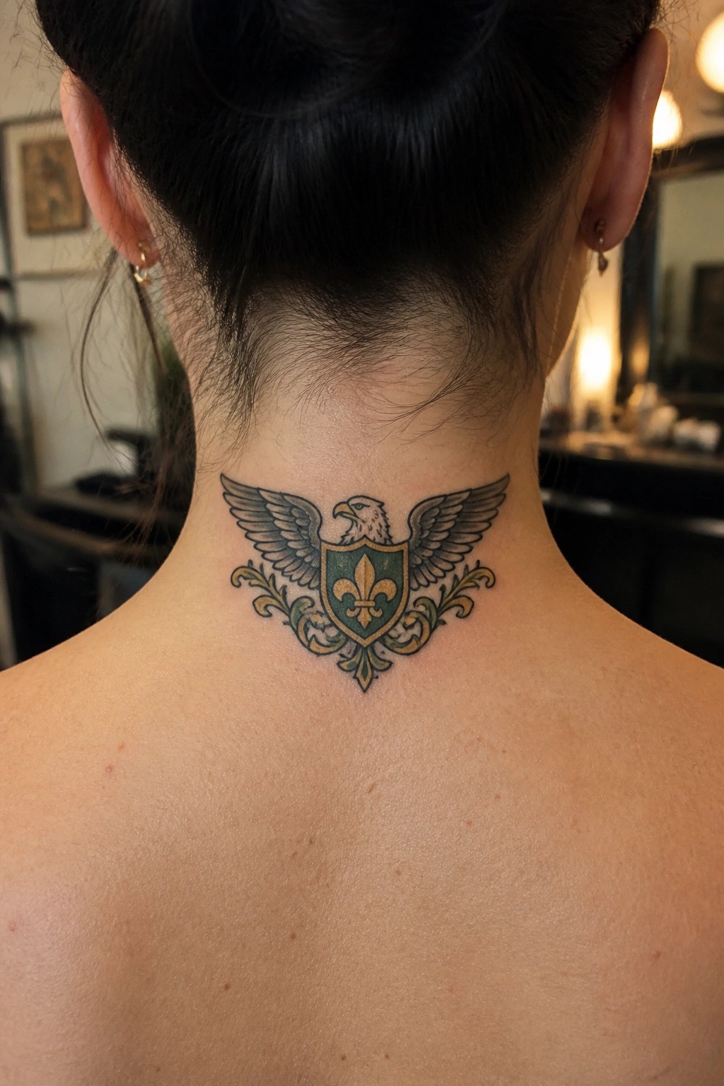 Intricate tattoo of winged eagle over green shield with fleur-de-lis on neck