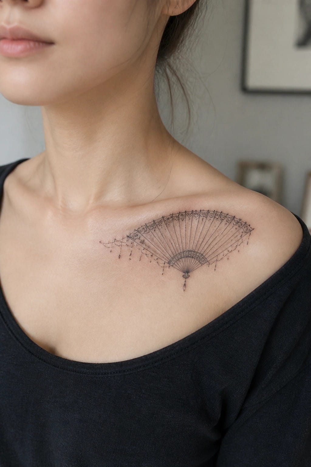 Woman in black off-shoulder top with ornate fan tattoo on shoulder