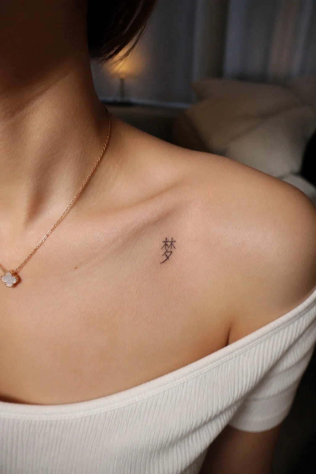 Small minimalist Chinese character tattoo on a woman's shoulder