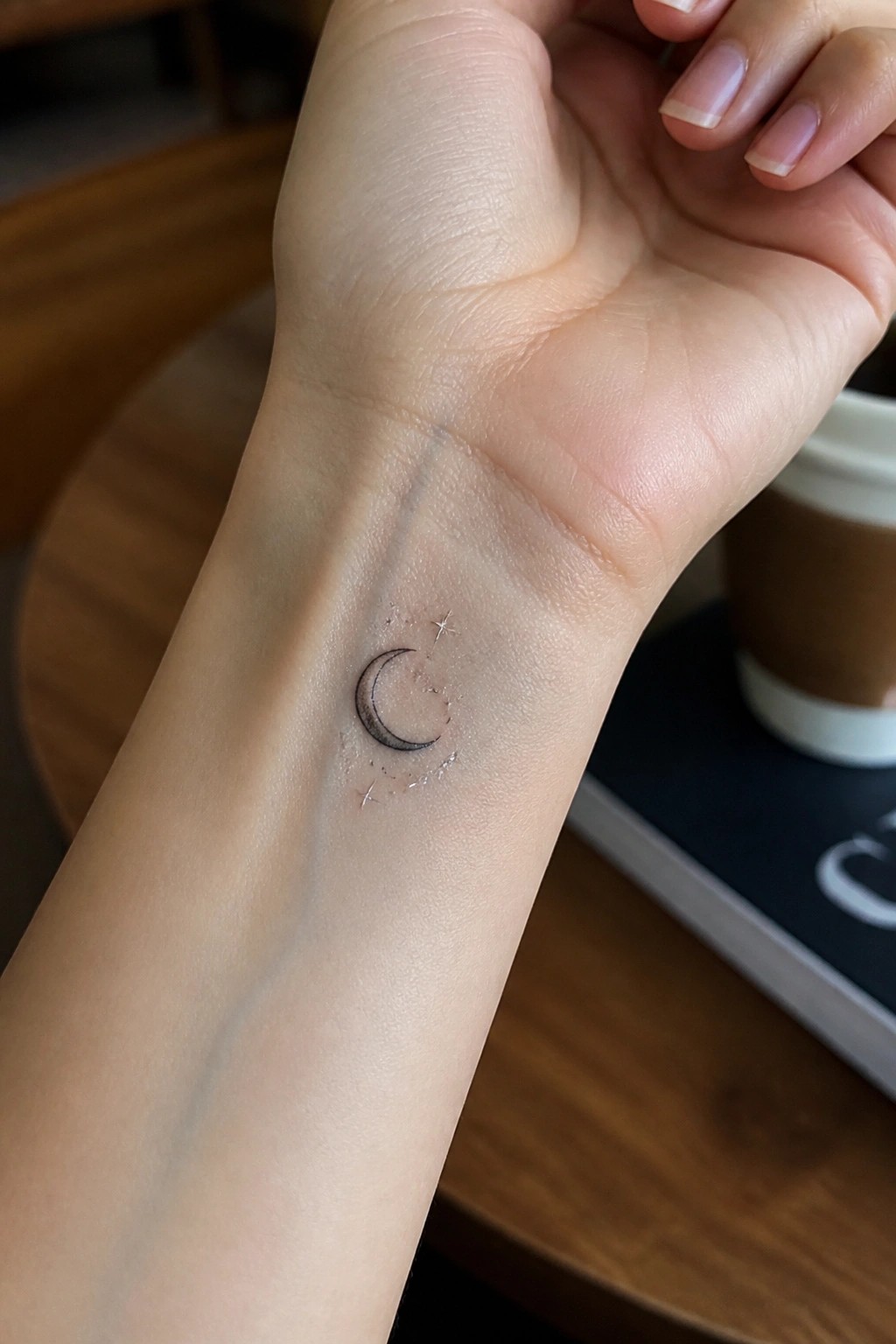 Small crescent moon tattoo with stars on the inner wrist in fine line style