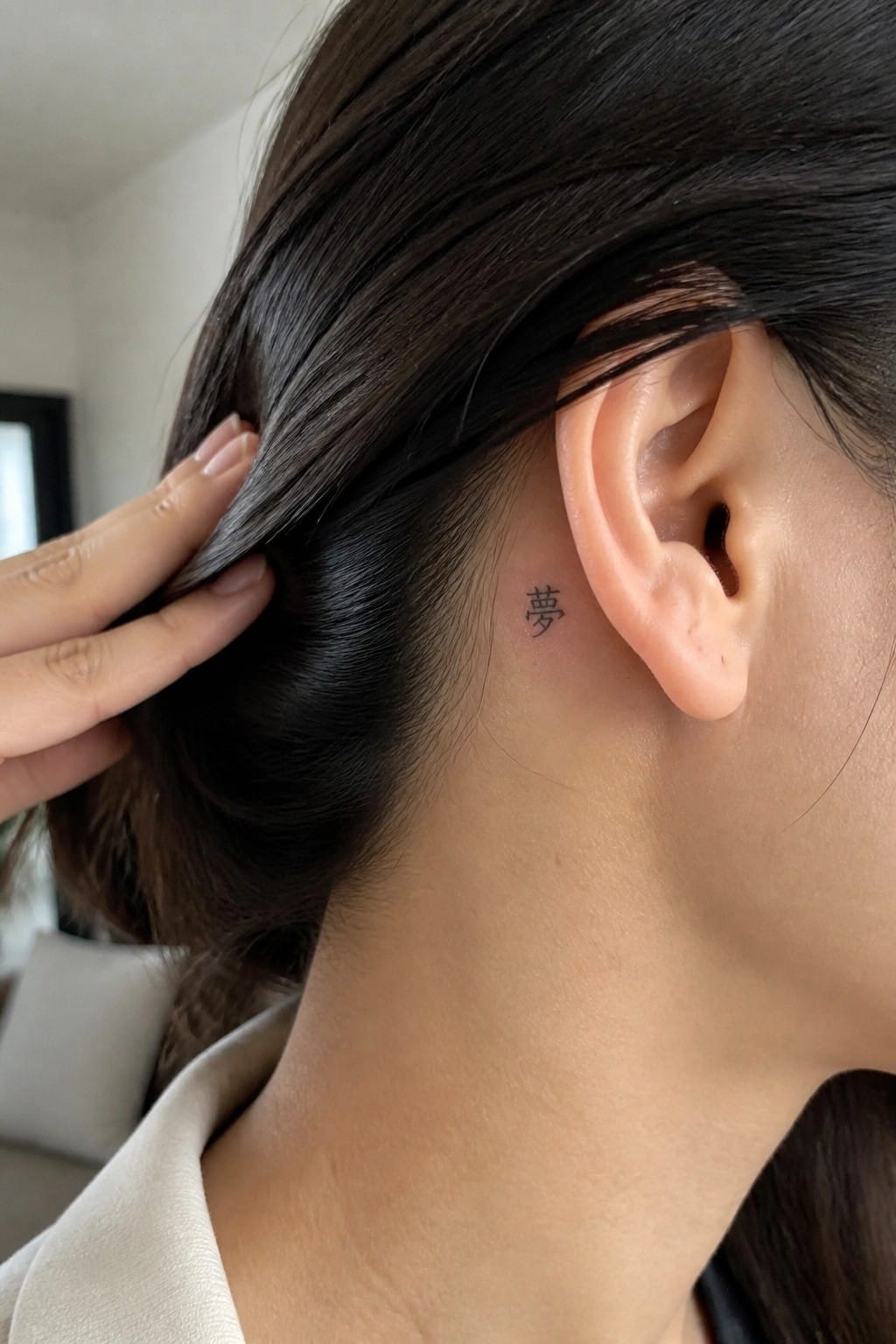 Small Chinese character tattoo placed behind the ear on the side of the neck