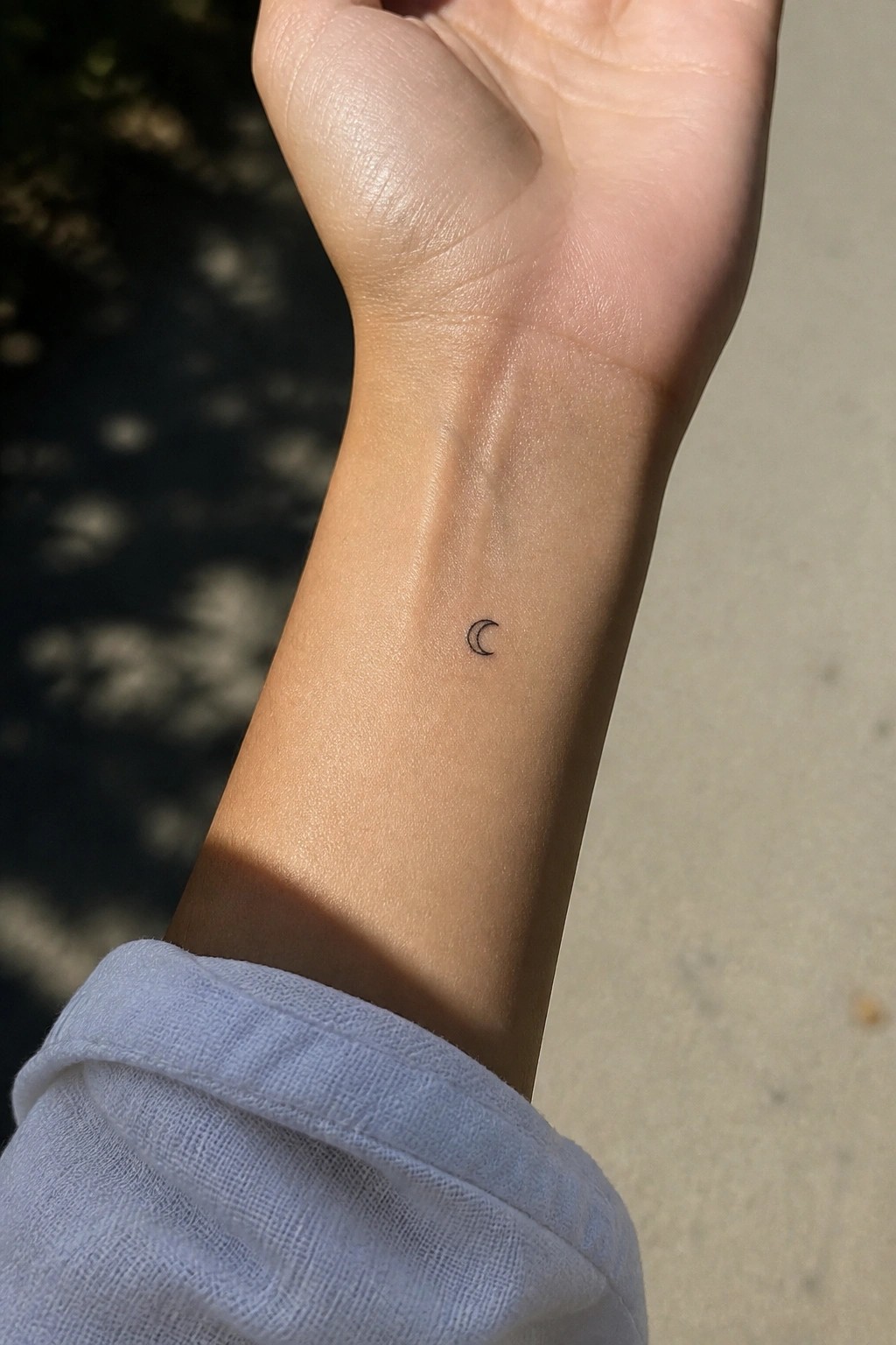 Small black crescent moon tattoo on the inner wrist