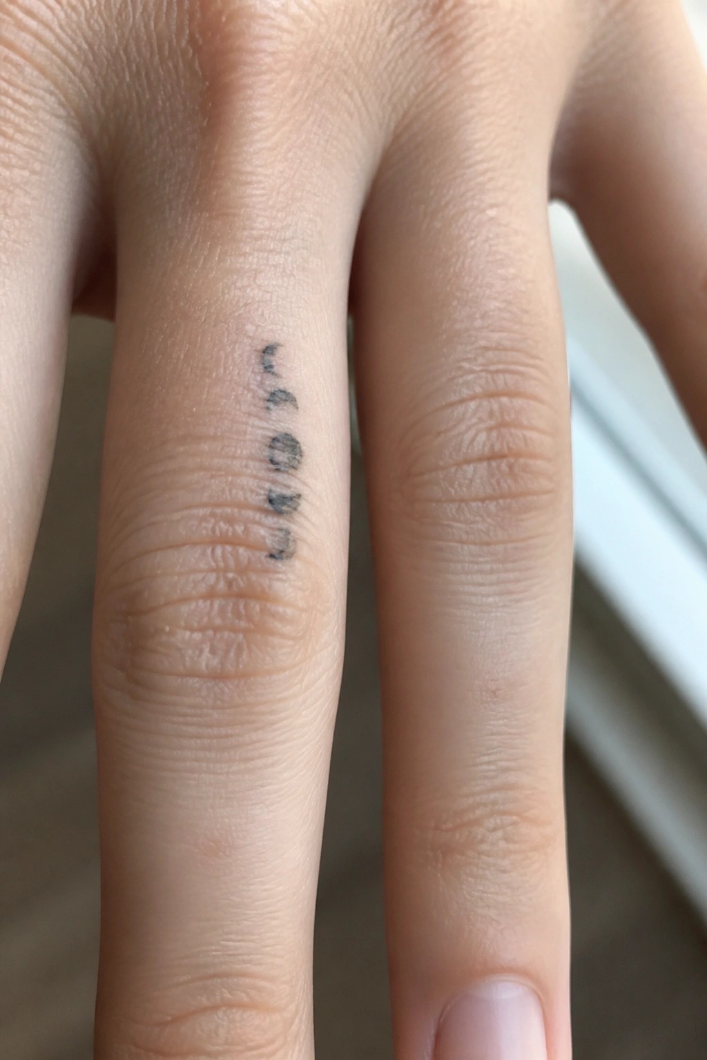 Hand with small vertical black tattoo spelling