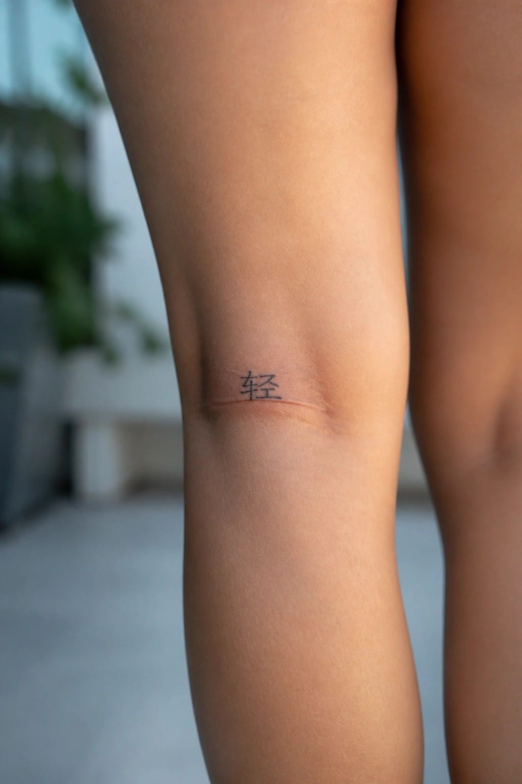 Knee close-up with small Chinese tattoo above a faint horizontal scar on skin