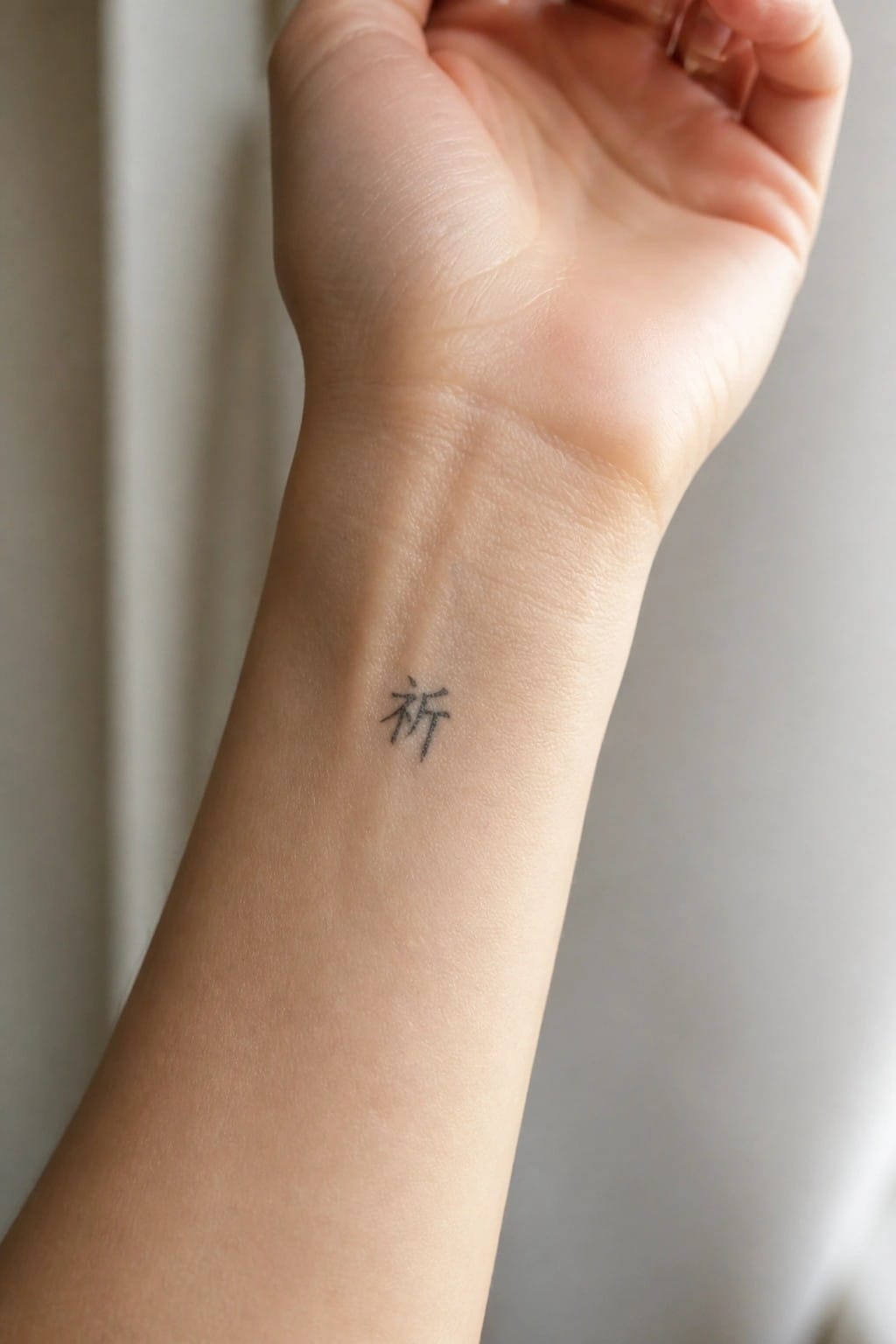 Small Chinese character tattoo on the inner wrist of a person's hand