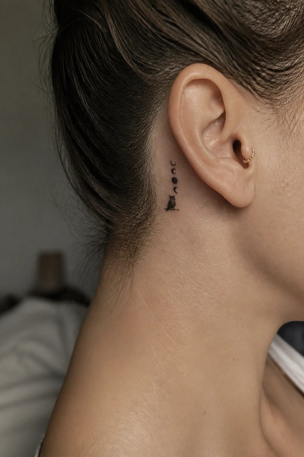 Moon phases and owl tattoo behind ear with small gold earring