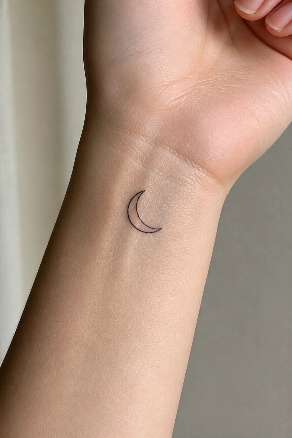 Fine line crescent moon tattoo on the inner wrist