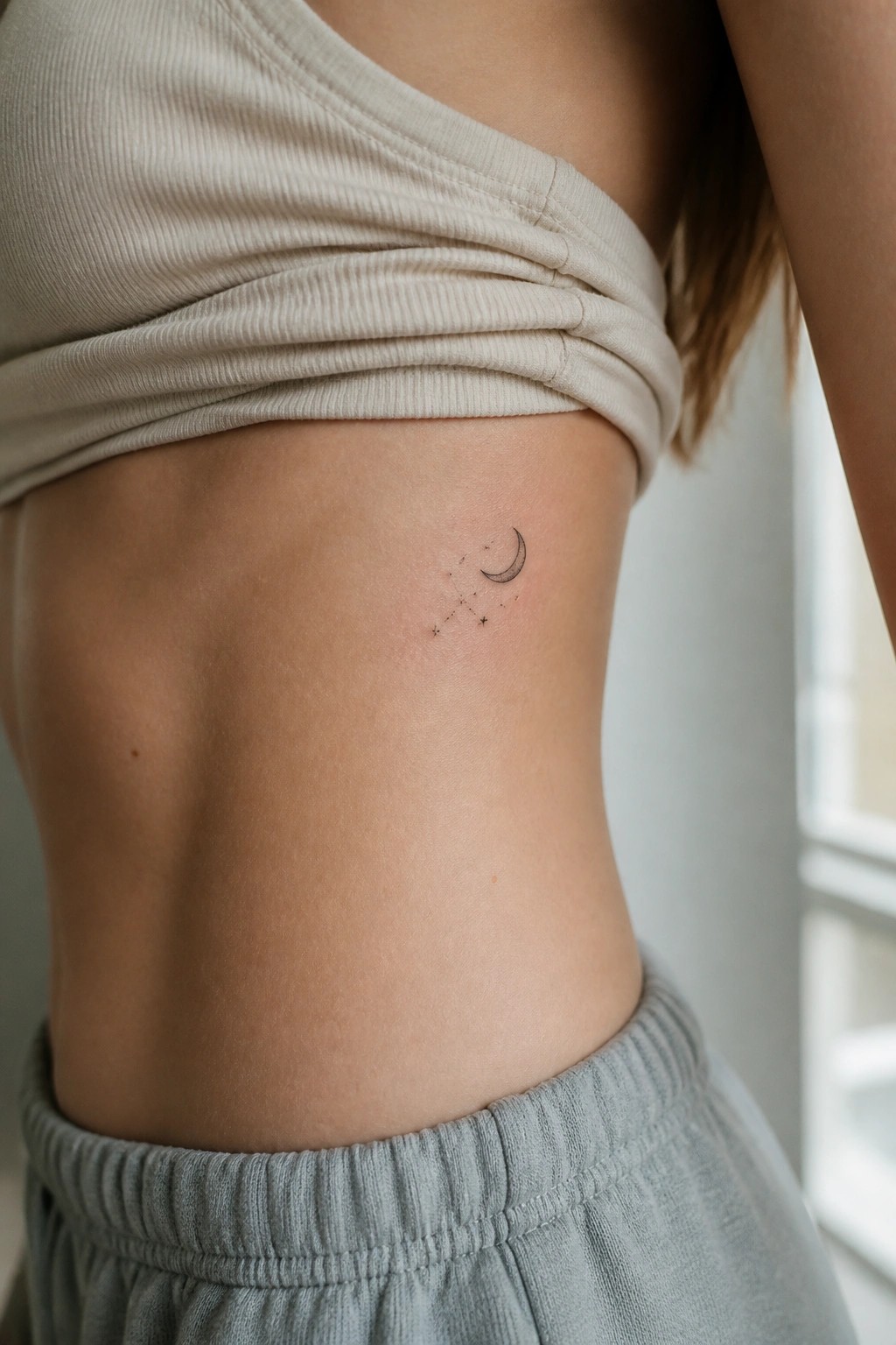 Beige ribbed top lifted revealing crescent moon and stars tattoo on side.