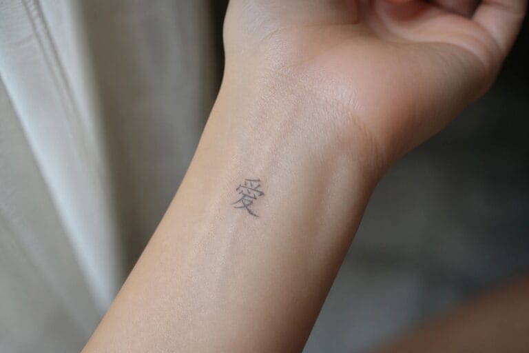 24 Small Chinese Tattoo Ideas for Women Perfect for First Tattoos Clenched hand with small black Chinese character tattoo on inner wrist.
