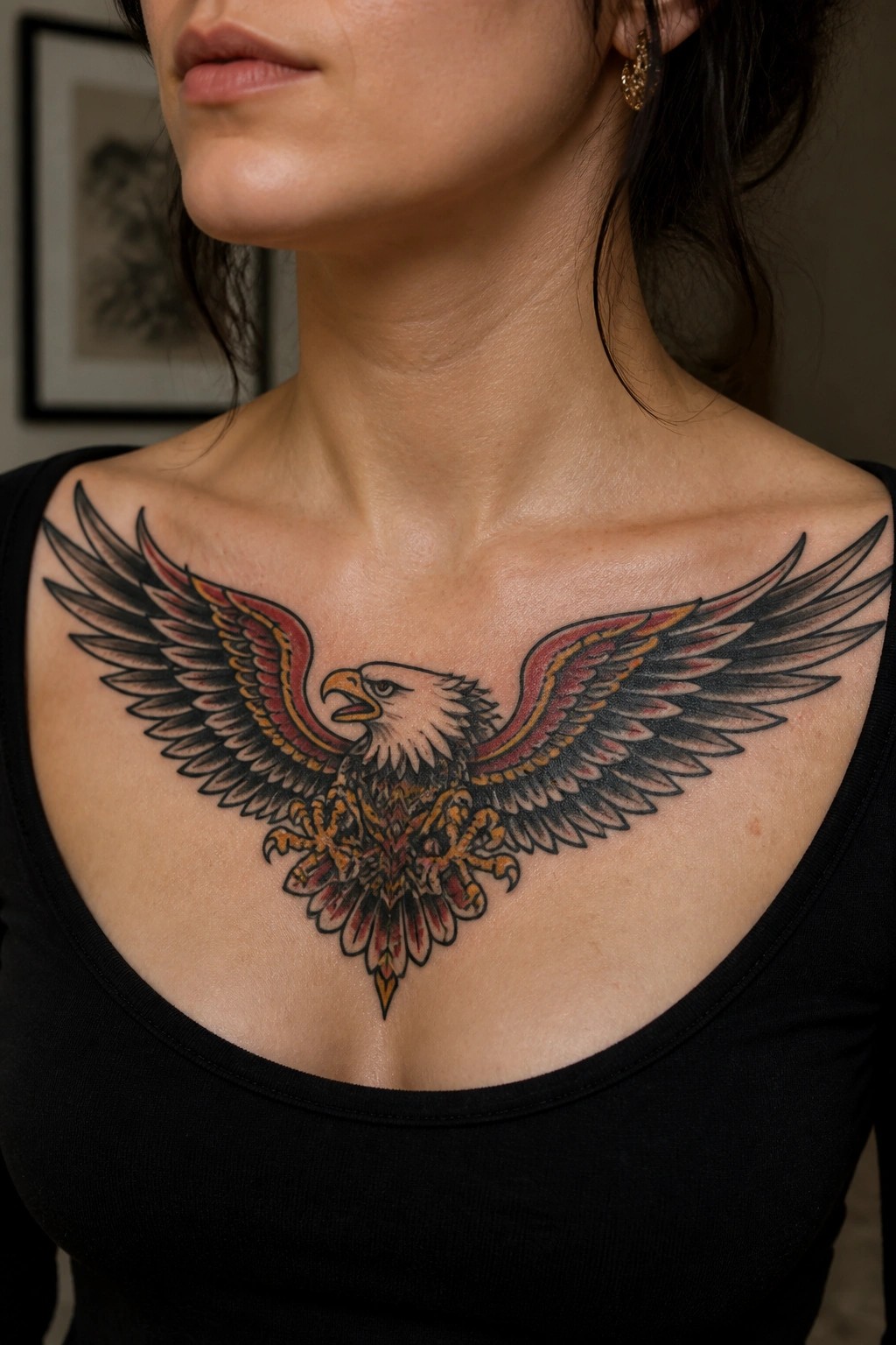 Large eagle tattoo with spread wings in red and black ink across a woman's upper chest