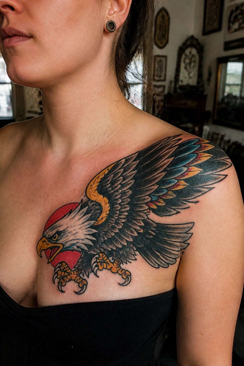 Woman in black top with large colorful eagle tattoo on shoulder and chest