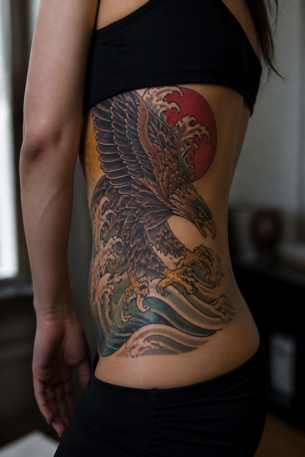 Large eagle tattoo on side torso with spread wings over waves and a red sun behind it.
