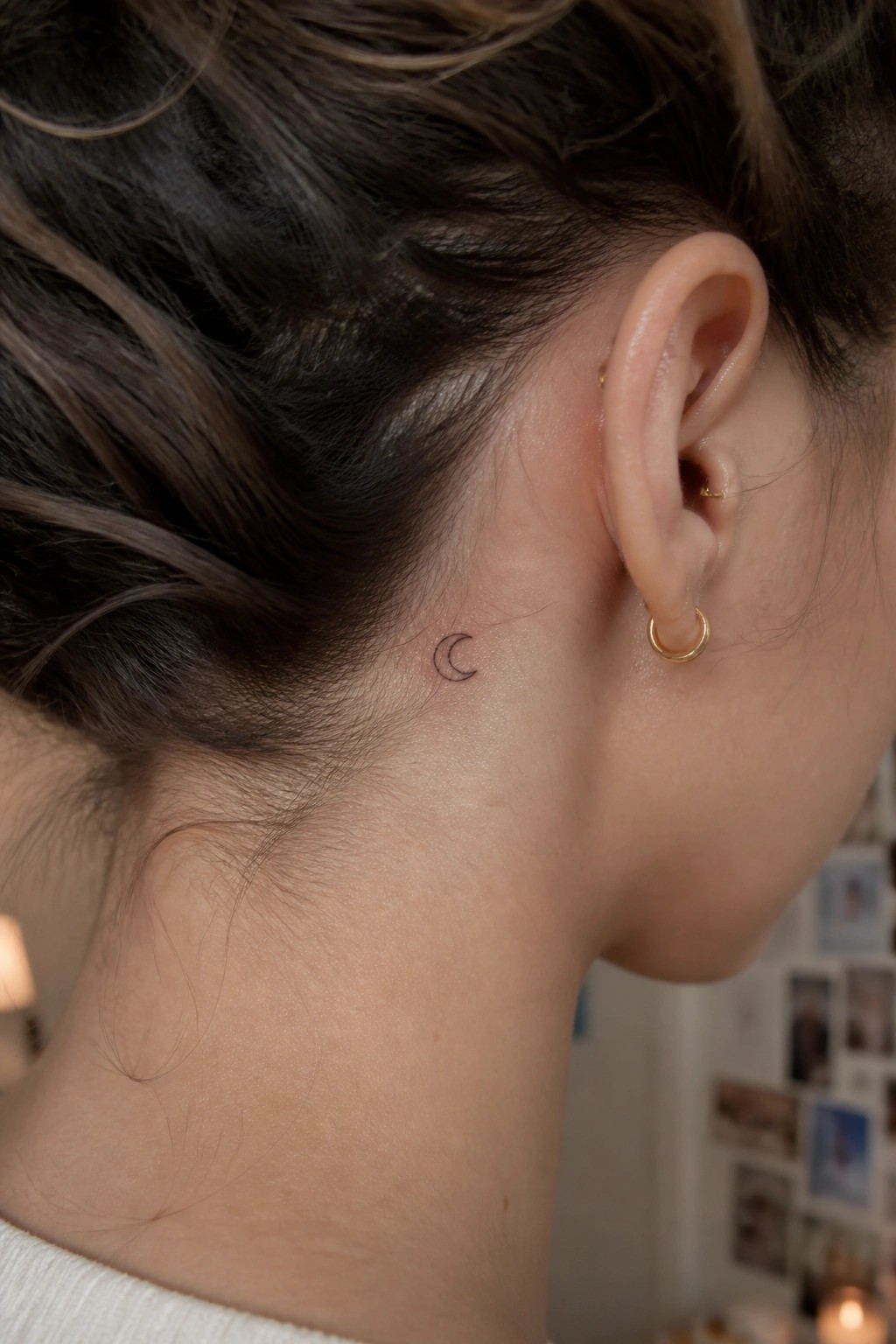 Fine line crescent moon tattoo placed behind the ear on the side of the neck.