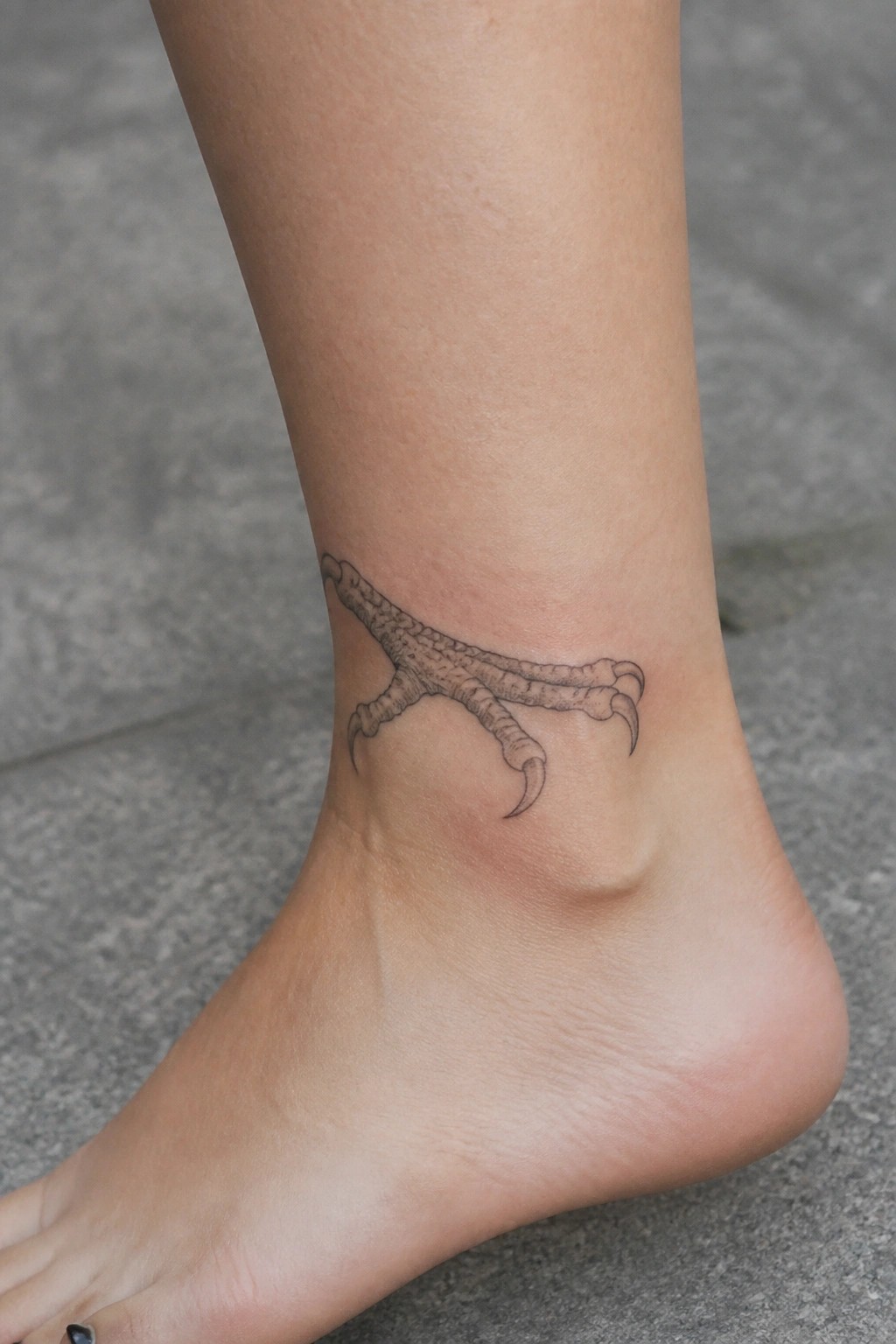 Bird claw tattoo on a bare ankle above the heel