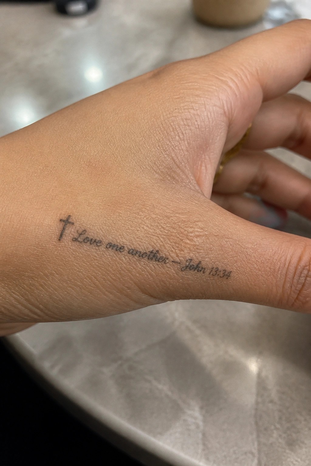 Hand with black ink tattoo of cross and 