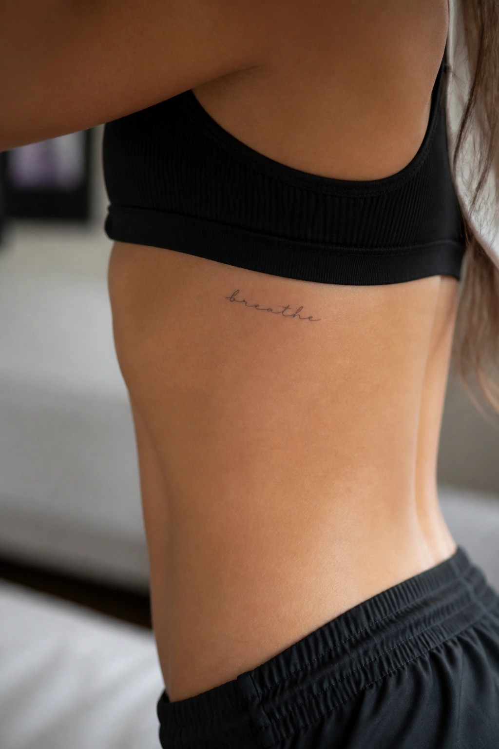 Torso in black sports bra with cursive