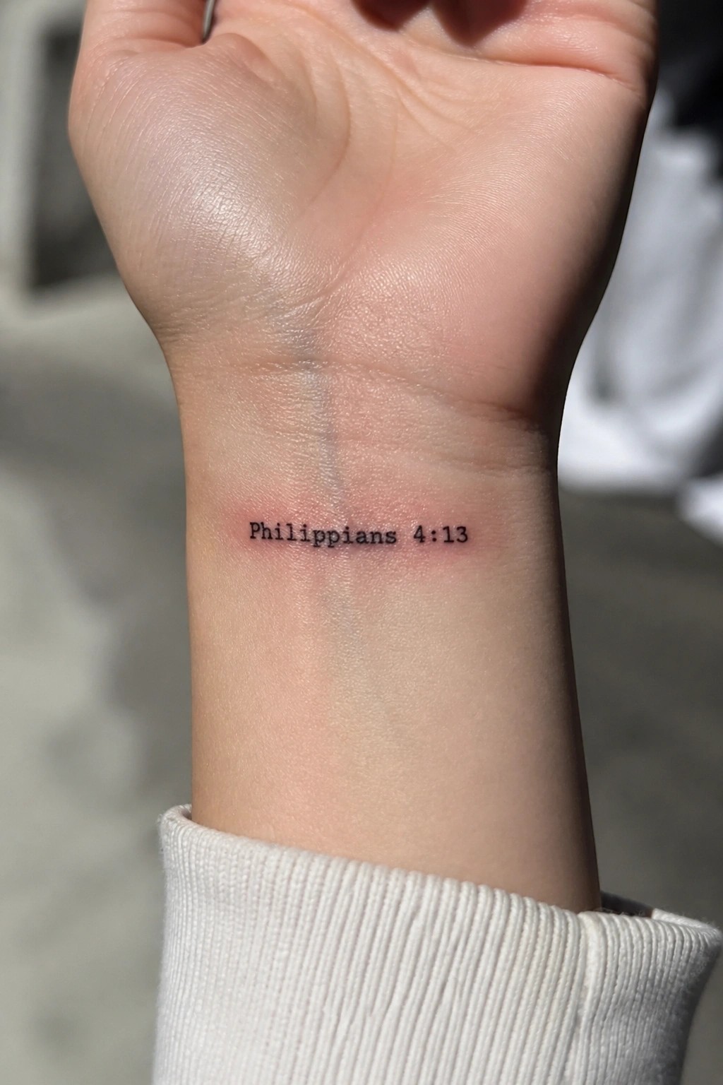 Wrist tattoo in black text