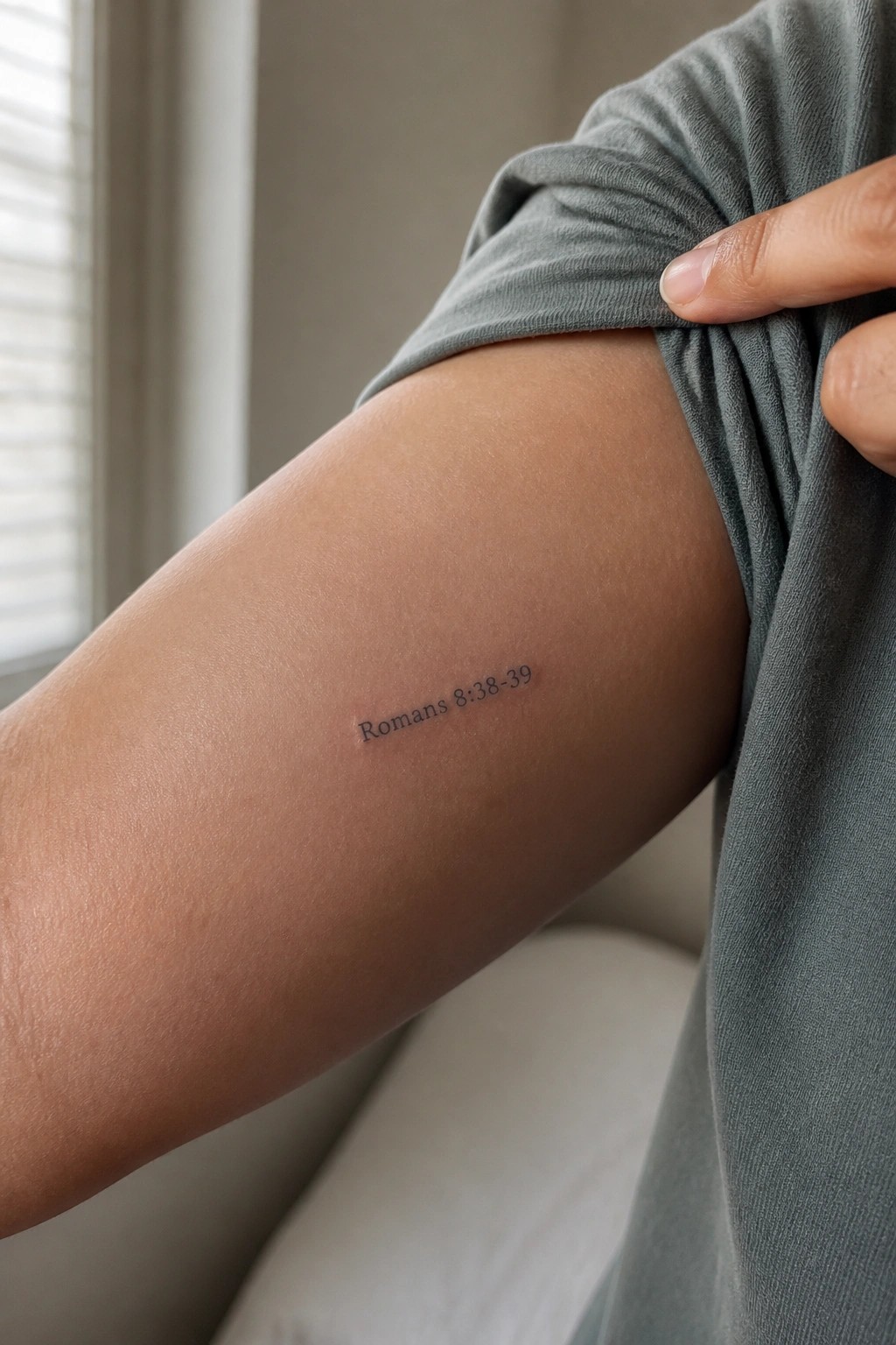 Small Romans 8:38-39 tattoo in simple script on the inner upper arm