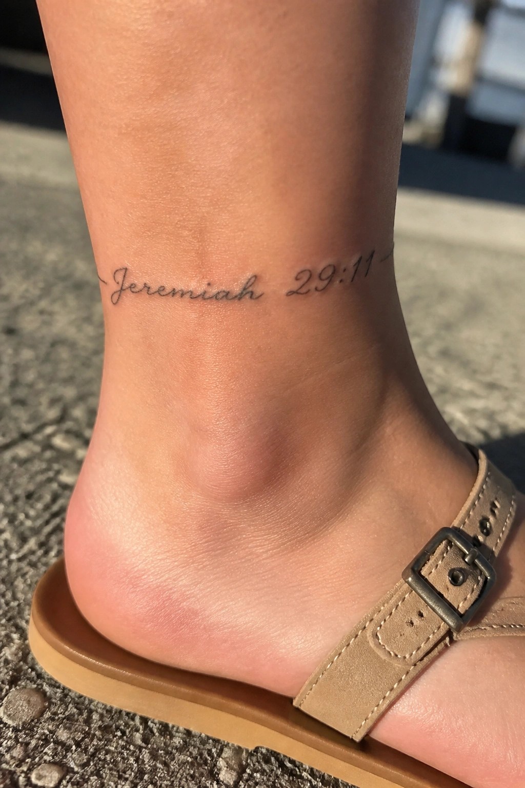 Ankle tattoo reading Jeremiah 29:11 above beige buckled sandal on foot