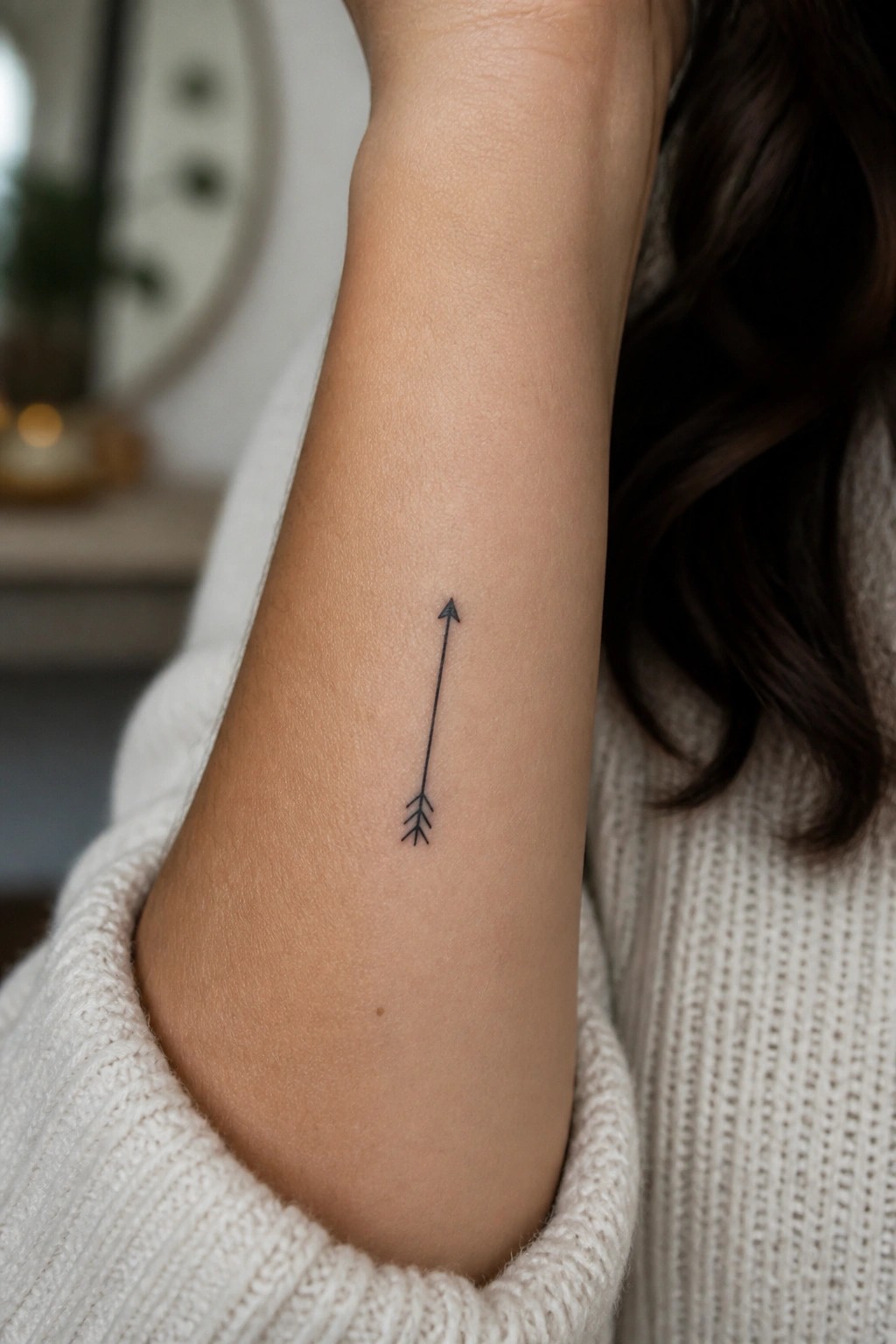 Small minimalist arrow tattoo in black ink on the inner forearm