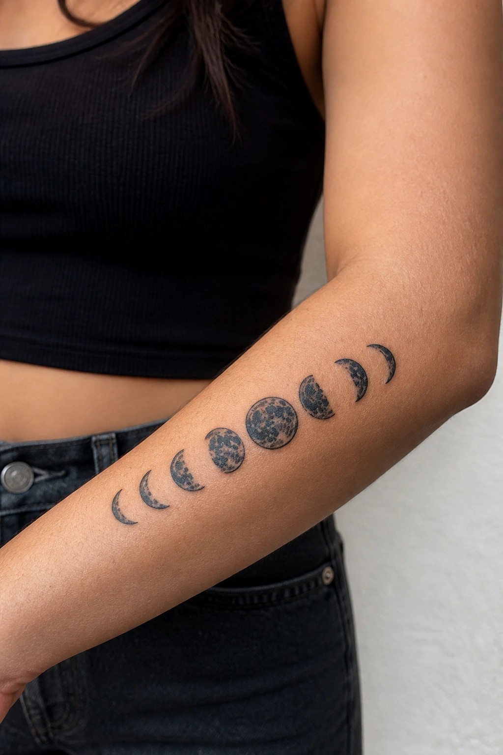 Realistic black ink moon phases tattoo arranged in a linear sequence on the inner forearm, showing the lunar cycle from crescent to full and back.
