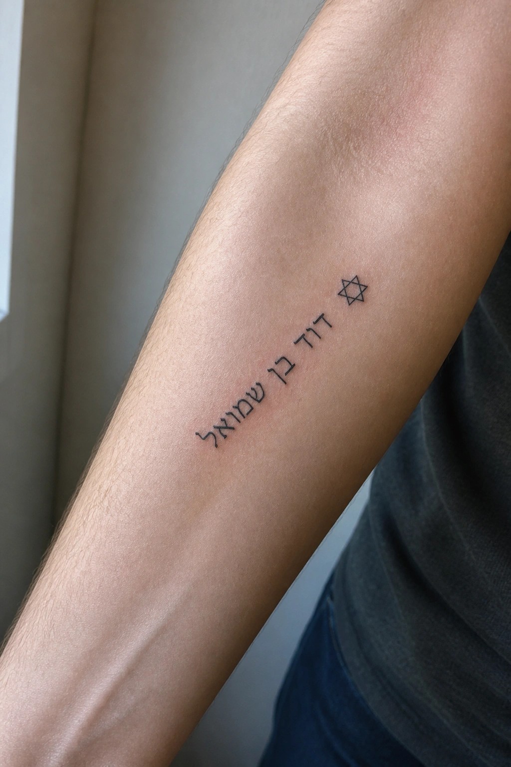 Hairy forearm with black Hebrew script tattoo beside Star of David symbol